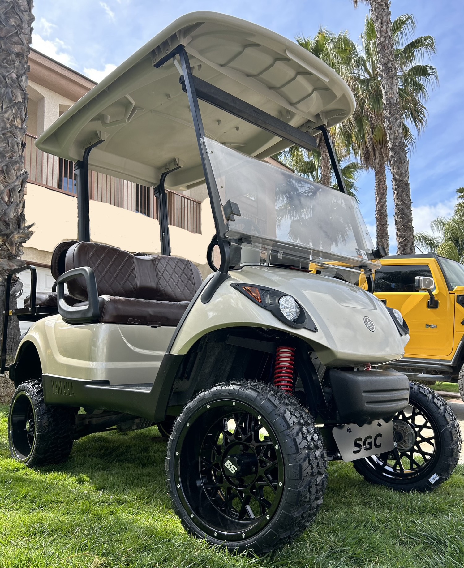 Lifted Yamaha golf cart with larger tires, a windshield, and dark wheels on a lawn